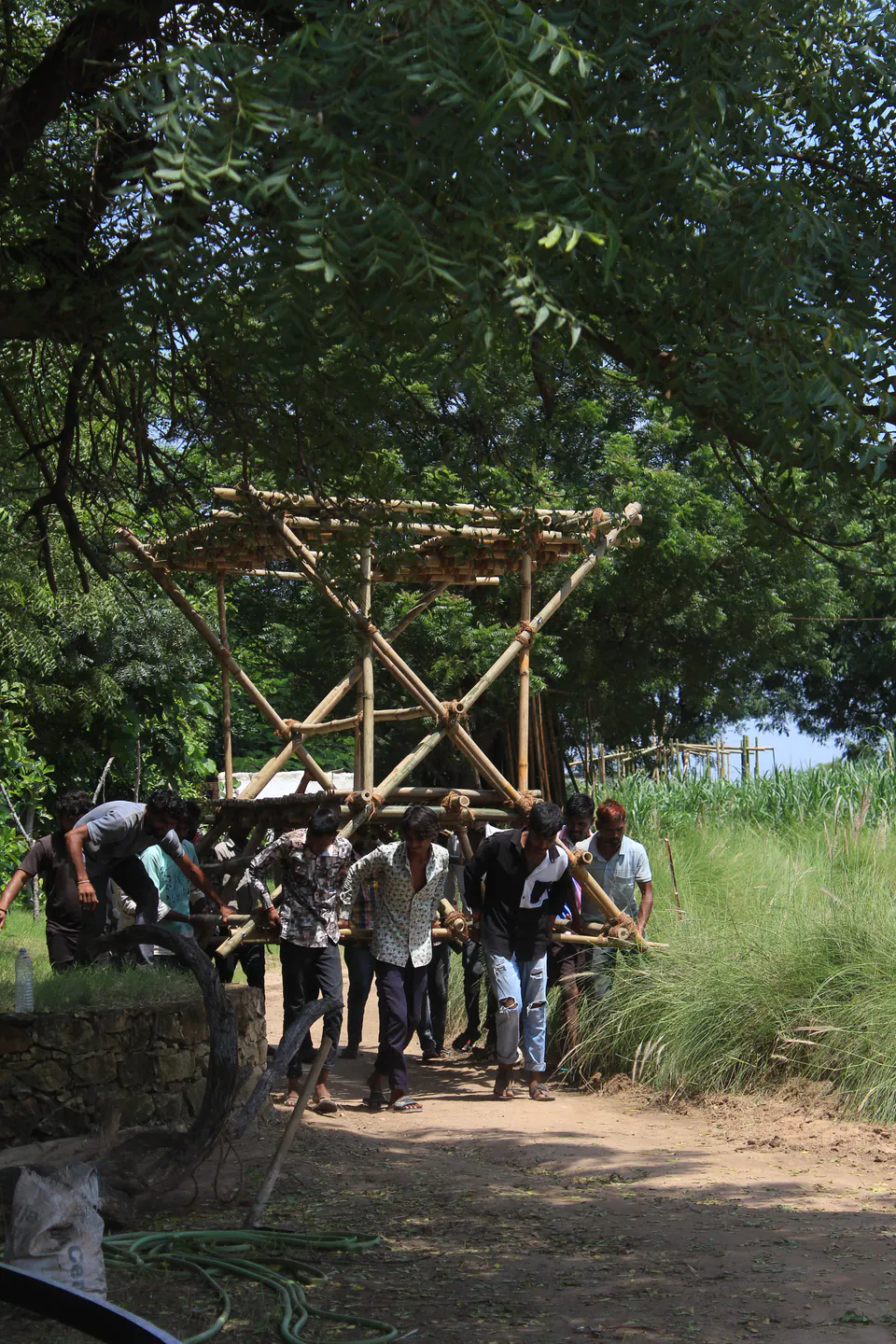 The build team lifting the bamboo frame of The X into place among trees